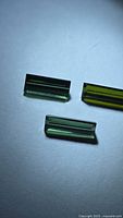 Three baguette-cut green tourmalines on light background