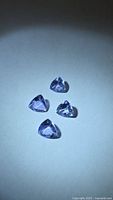 Four loose trillion-cut tanzanite gemstones on white background