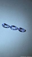 Three oval-cut light purple tanzanites on neutral background
