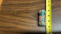 Full view of cloisonné cylinder case next to ruler showing height