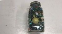 Front view of filled jar showing variety of marbles and lid