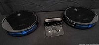 Two Eufy RoboVac vacuums with charging dock between them