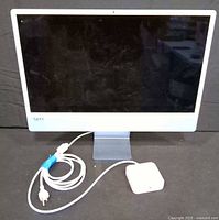 Front view of blue 24-inch iMac with white bezel, stand and power accessories visible