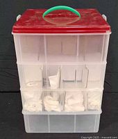 front view of four-tier clear plastic bin with red lid and green handle