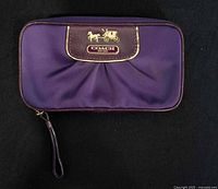 Front view of purple Coach jewelry case showing horse-and-carriage logo