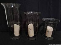 Three glass vases each containing a flameless candle