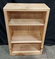 Front view of entire bookcase showing three shelves and unfinished pine wood