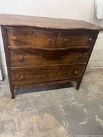 Front view showing four drawers, serpentine front, knobs, overall wear