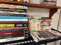 Overview of stacked graphic novels, manga volumes and game books on shelves
