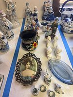 Overview showing Delft-style figurines, black pottery cup, portrait plaque, mini tea set, busts and glass dish