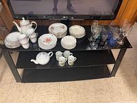 Overall view of porcelain pieces, stacks of plates, teapot and cups on shelf