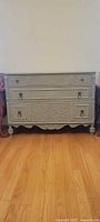 Full front view of carved three-drawer dresser