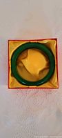 Overhead view of green jade bangle in yellow satin-lined red box