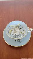 Top view of teacup resting on saucer showing floral design and gilt edges