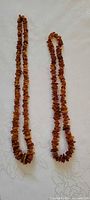 Both Baltic amber necklaces laid flat showing chip style and relative lengths