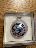 Front view of ornament showing Blue Jays World Champions 1992 logo inside plastic box