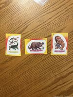 Front view of three 1988 Topps Dinosaurs Attack! stickers: Plesiosaurus, Triceratops, Allosaurus