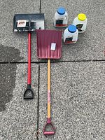 Entire lot showing both shovels and three ice melter jugs on pavement