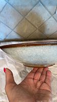 Side profile of cream crackle glaze oval bowl showing brown rim