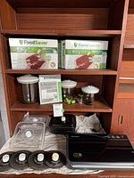 Overall shelf view with vacuum sealer rolls, canisters, lids and appliance