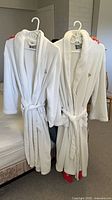 Two white Kanata bathrobes hanging, belts visible