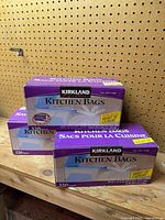 Three sealed purple Kirkland Signature Kitchen Bags boxes on shelf