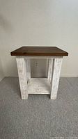 Full view of end table front showing square top, whitewashed legs, lower shelf