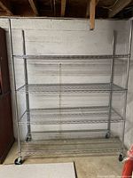 Full view of chrome wire shelving rack showing four shelves and casters