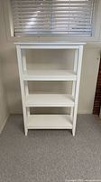 Front view of white open bookcase showing three shelves and top