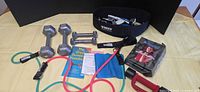overview of dumbbells, bands, belt, gloves, booklet, VHS, mat