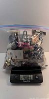 Front view of sealed bag on scale showing 4063 g (~4 lb) of mixed jewelry pieces