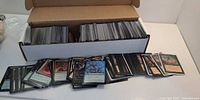 Top view of open 800-count box filled with Magic cards, additional cards spread out in front