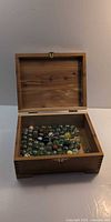 Open wooden box showing interior filled with marbles