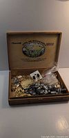 Open wooden cigar box showing assorted jewelry pieces