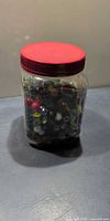 Full view of jar with red lid filled with marbles