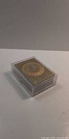 Closed clear plastic case with top card showing gold circular limited edition seal