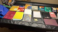 Overall view of assorted paper products, labels, folders, notebooks, pads on table