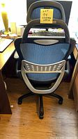 Rear view of mesh high-back chair showing headrest, lumbar frame and five-star base