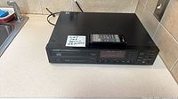 Top view of Denon DCD-1500 CD player with remote resting on unit