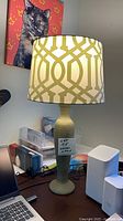 Full view of table lamp on desk showing green base and patterned shade