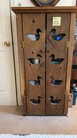 Front view of closed cabinet showing duck cutouts and brass hinges