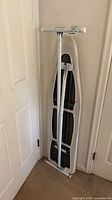 Ironing board folded and leaned against wall