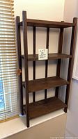 Full view of four-tier wooden shelving unit against wall