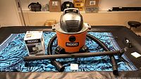 RIDGID wet/dry shop vacuum with hose, two wands and boxed filter displayed on table