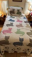 Full view of twin bed with cat quilt and matching sham