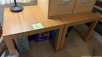 pair of light wood laminate tables under drawer unit
