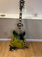 Full frontal view of Ibanez green fade semi-hollow guitar on stand with strap attached