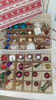 Open storage box showing assorted ornaments in dividers, votives, picks