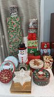 Overview of entire assortment showing stacked holly boxes, snowman tins, various round tins, star box and others