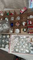 Overview of boxed glass ball ornaments, packaged silver/white ball set and bag of clear plastic icicles